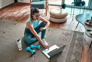 woman sitting with workout equipment with laptop