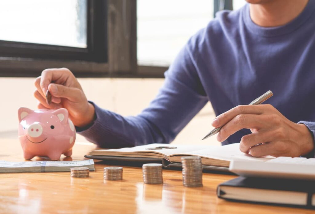 man sorting coins and putting the change in piggy bank